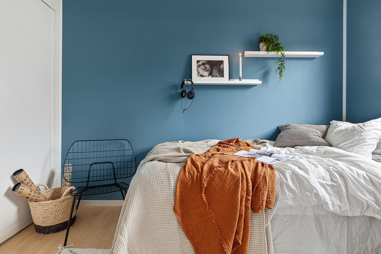 A bedroom with one wall painted a soft denim blue